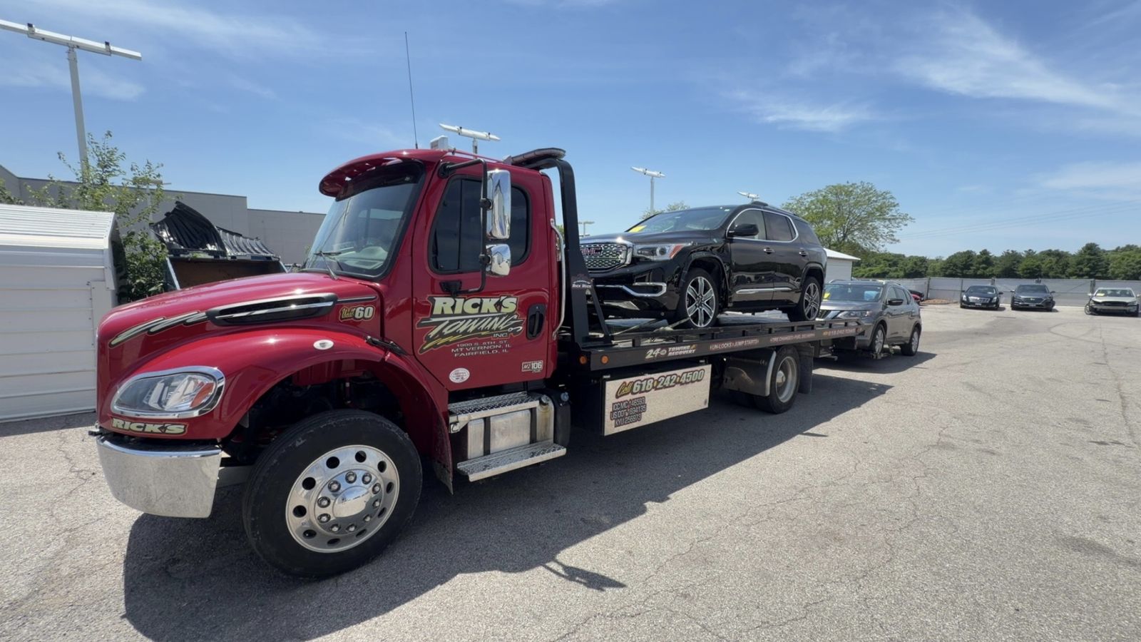 Rick's Towing Unit 60 rollback hauling an SUV with a second car in tow